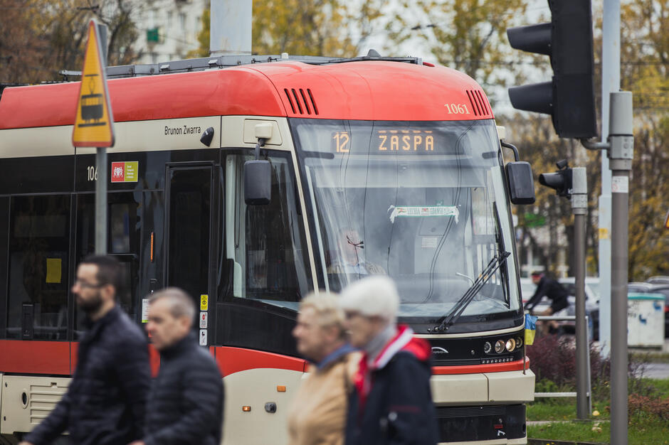 Tramwaj na przystanku, na pierwszym planie piesi.