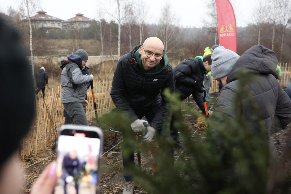 mężczyzna klęczy obok roślin, sadzonek