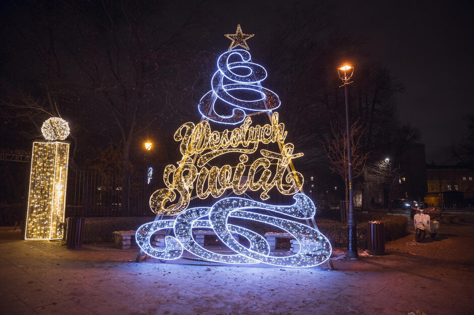 na zdjęciu rozświetlona choinka i iluminacja na bramie wejściowej