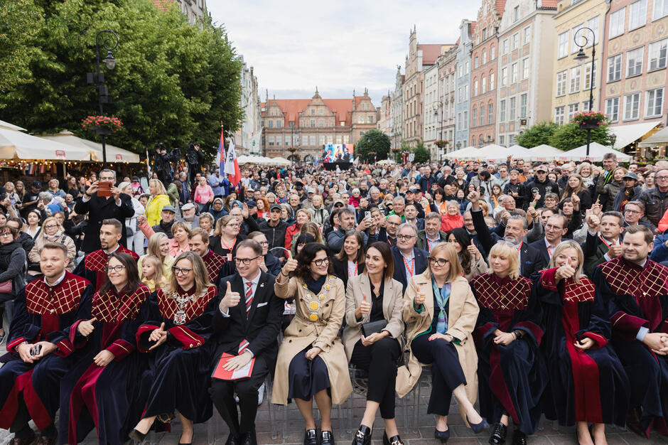 Duża grupa ludzi siedzi na ulicy starego miasta 