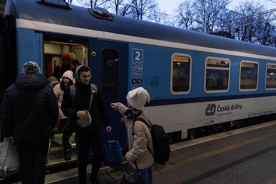 Wagon kolejowy na stacji, z którego wysiadają pasażerowie.