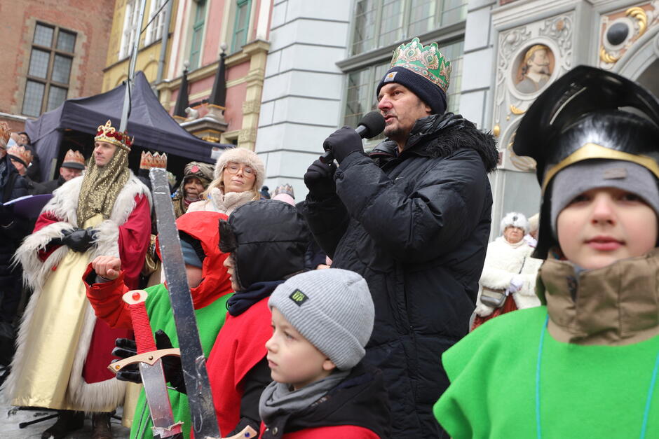 tłum ludzi, w tym dzieci, mężczyzna w środku tłumu przemawia przez mikrofon 