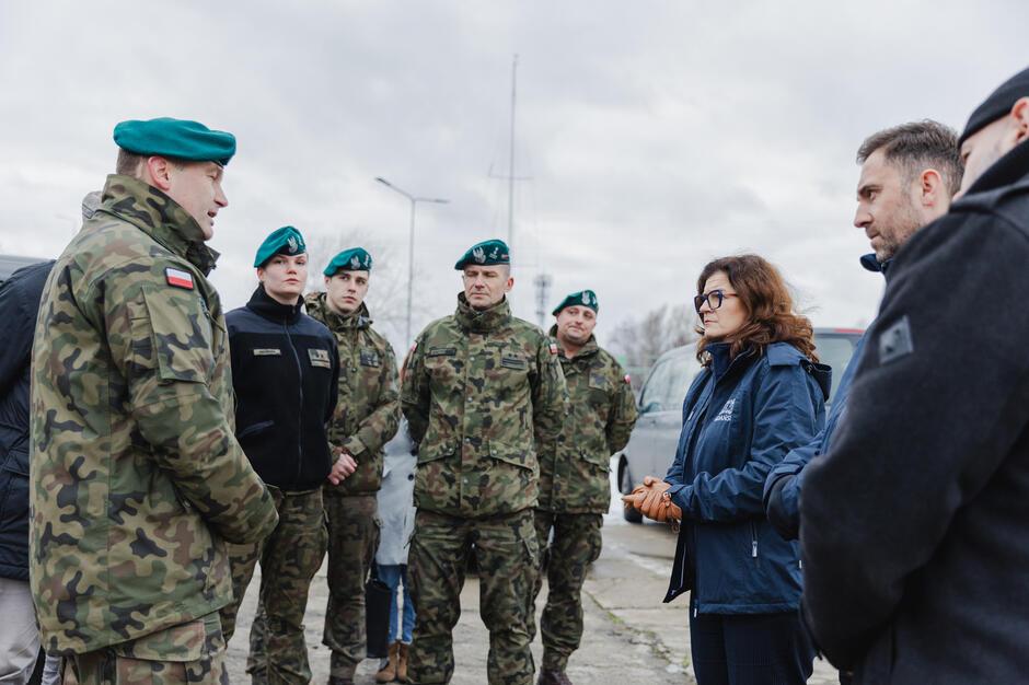 na zdjęciu grupa kilku żołnierzy w mundurach, naprzeciwko nich kilka osób w cywilnych strojach, rozmawiają