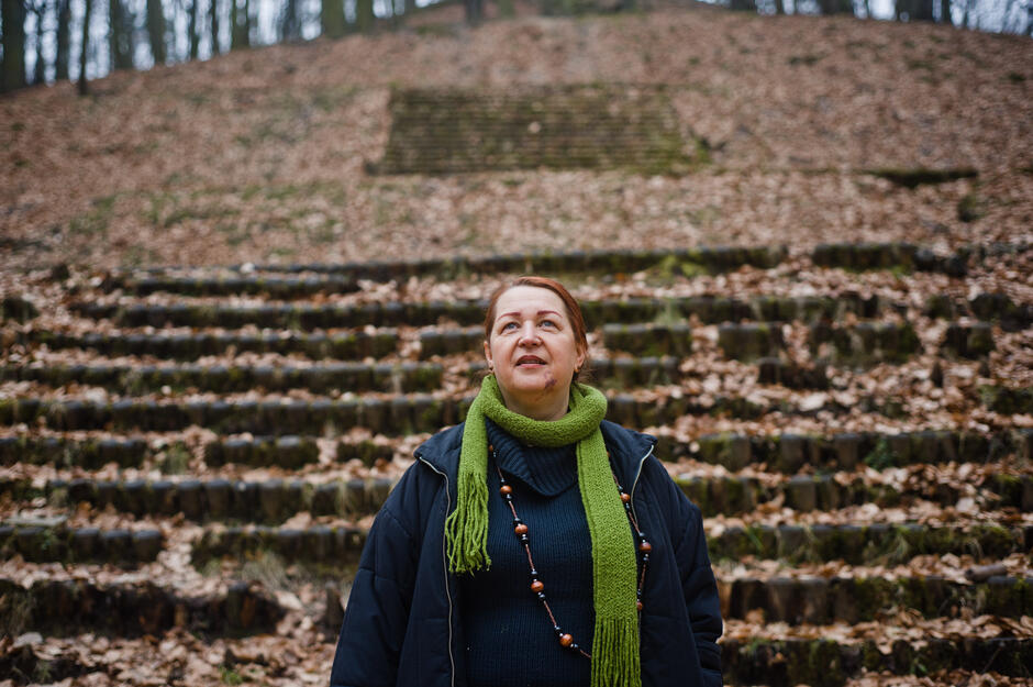 kobieta stoi na tle rzędu siedzeń w teatrze w lesie