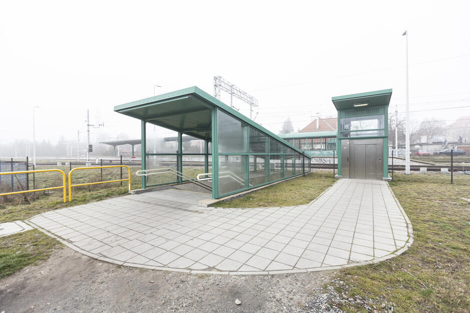 na zdjęciu wyjście z tunelu kolejowego, widać zielone przeszklone estetyczne wiaty i nowy równy chodnik