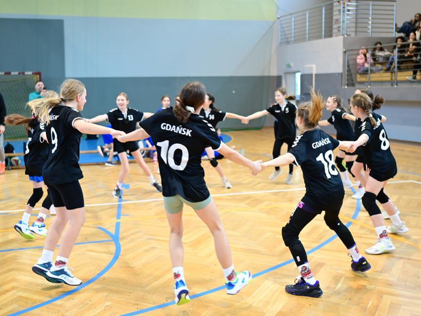 Dziewczynki w czarnych strojach tańczą w kółku