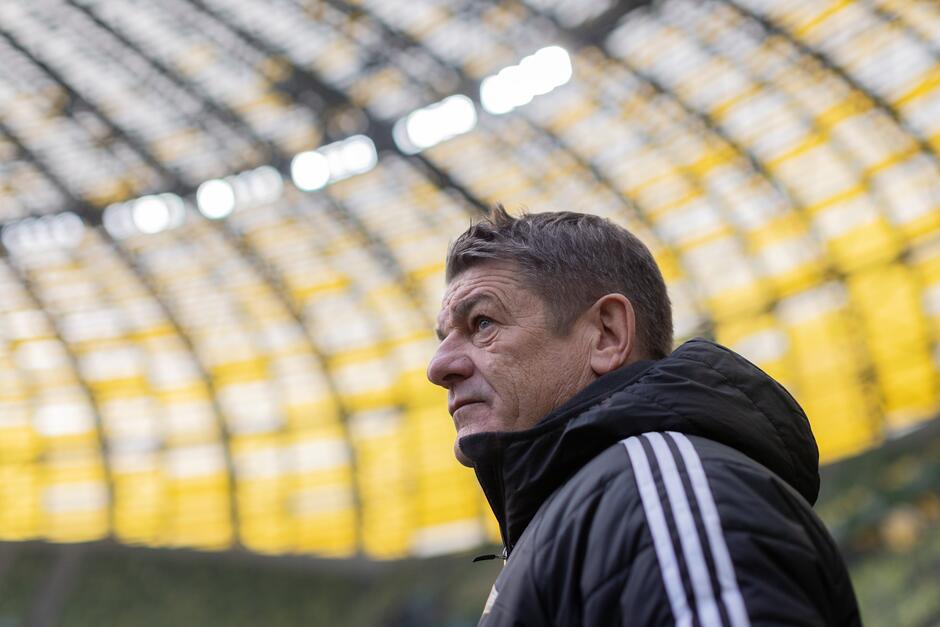 Zdjęcie mężczyzny lat około 60, na tle wewnętrznej korony stadionu Polsat Plus Arena Gdańska