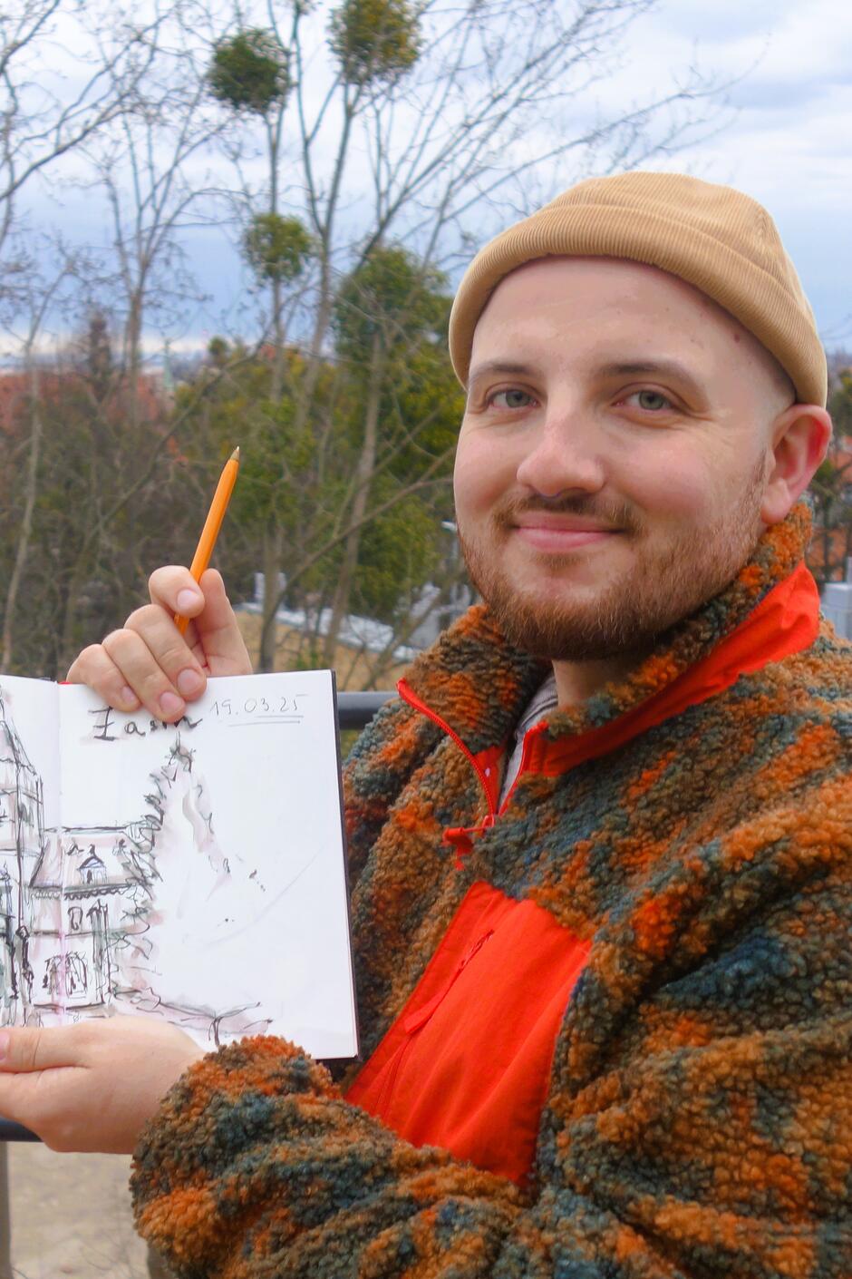 Rysownik Kamil Mączkowski na szczycie Biskupiej Górki prezentuje swój szkicownik
