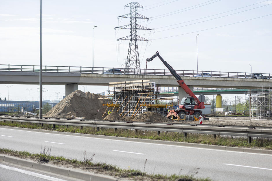 plac budowy na zdjęciu, widać duży dźwig skierowany w kierunku nowej konstrukcji filaru mostu