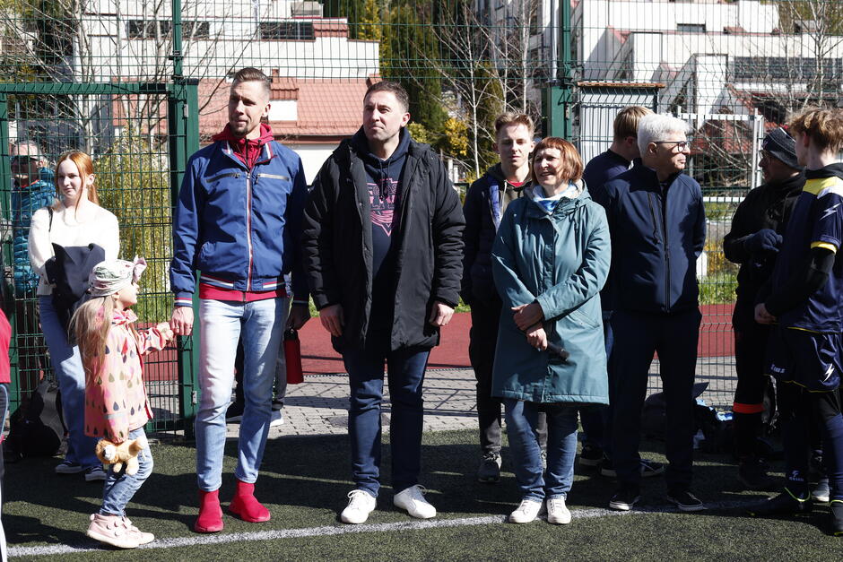 Grupa dorosłych stojących na boisku do piłki nożnej.