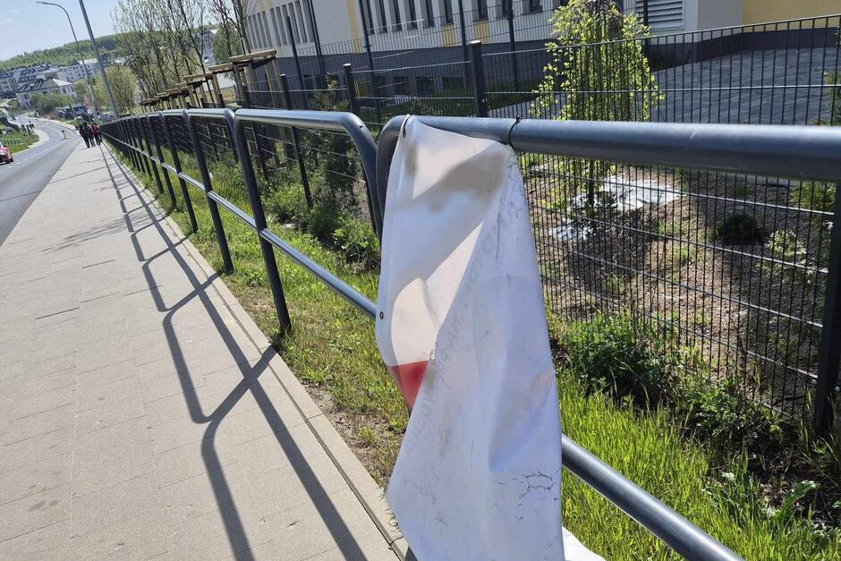 Częściowo zerwany baner na ulicznym ogrodzeniu