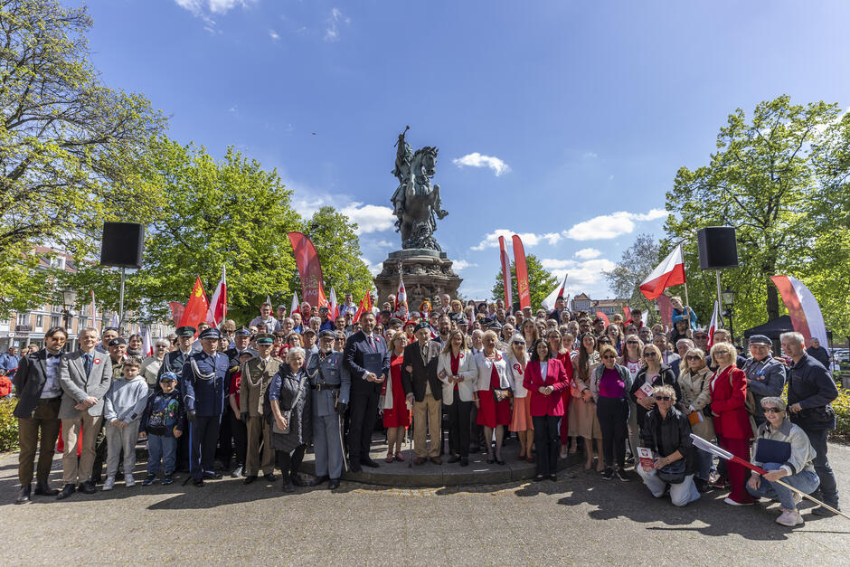 Grupa ponad 100 osób na zdjęciu pod pomnikiem 