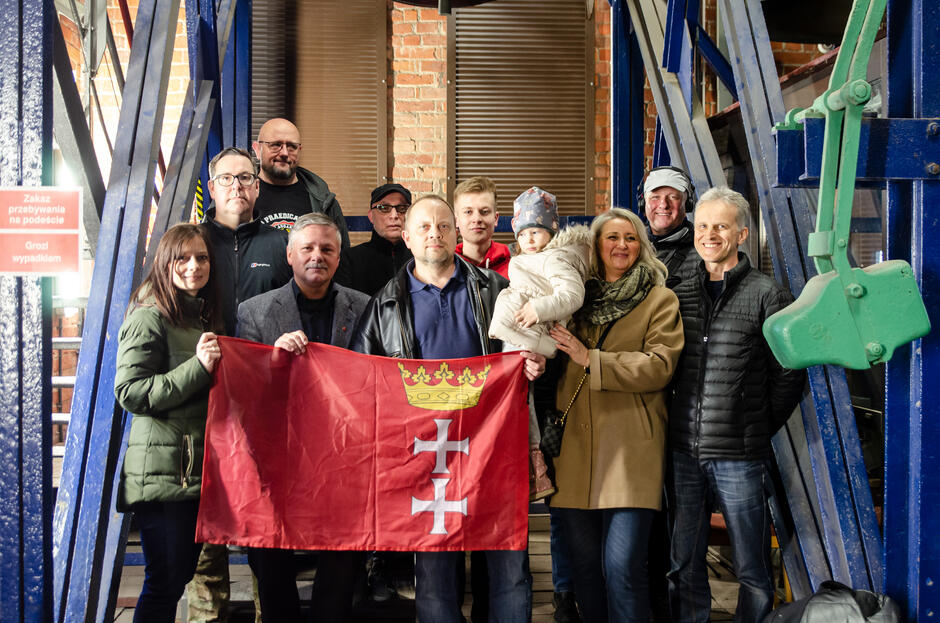 Grupa 10 osób pozuje do zdjęcia z flagą Gdańska