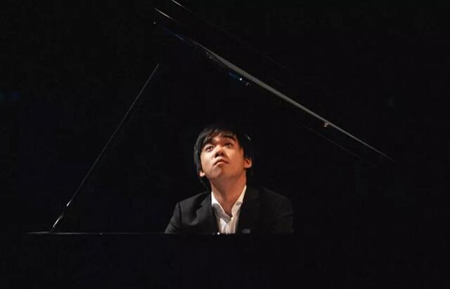 zdjęcie przedstawia pianistę Kevina Chena przy fortepianie, uchwyconego w skupieniu podczas gry