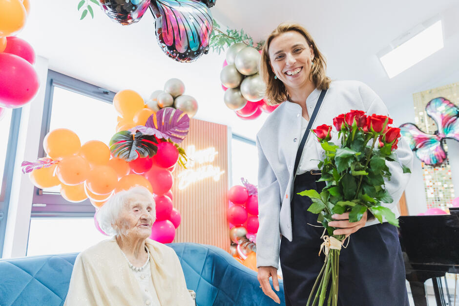 kobieta z kwiatami obok staruszka