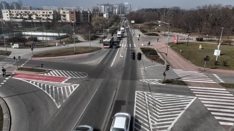 na zdjęciu duże skrzyżowanie ulicy z wymalowanymi na jezdni znakami i sygnalizacją świetlną