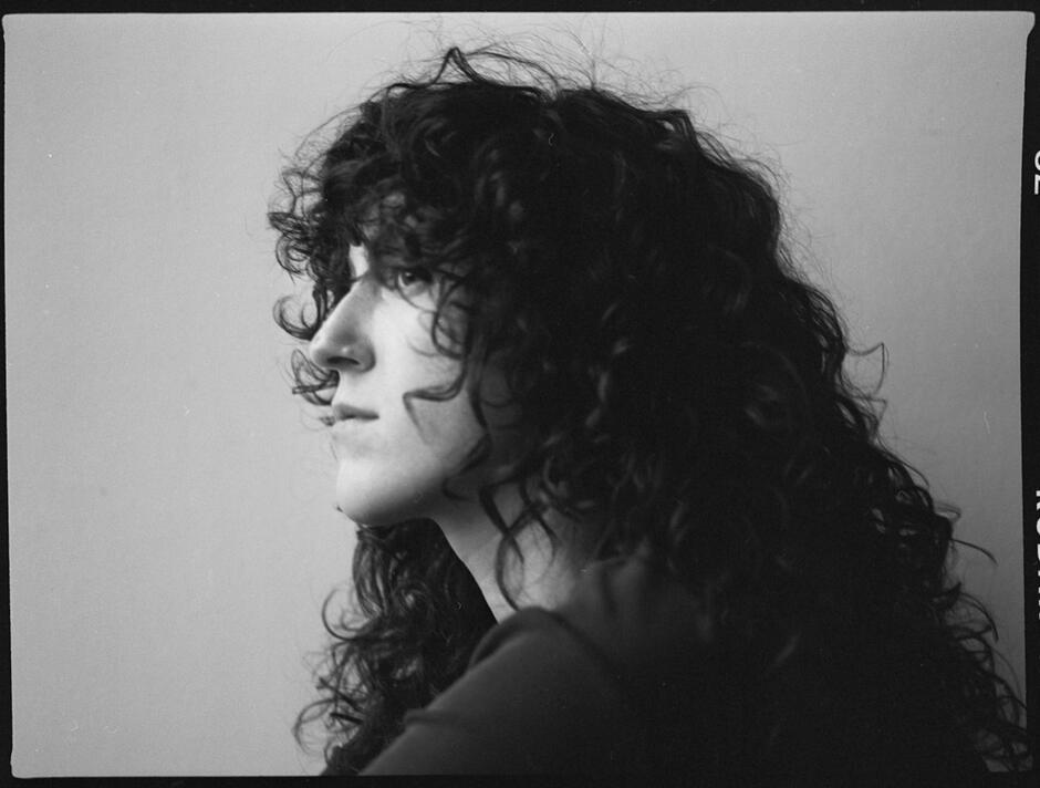 Zdjęcie przedstawia lewy profil kobiety o kręconych włosach