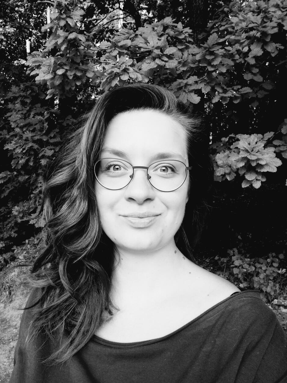 Na zdjęciu uśmiechnięta kobieta w okularach z włosami na ramionach