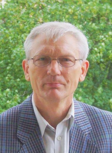 Zdjęcie przedstawia twarz mężczyzny w okularach, w garniturze.