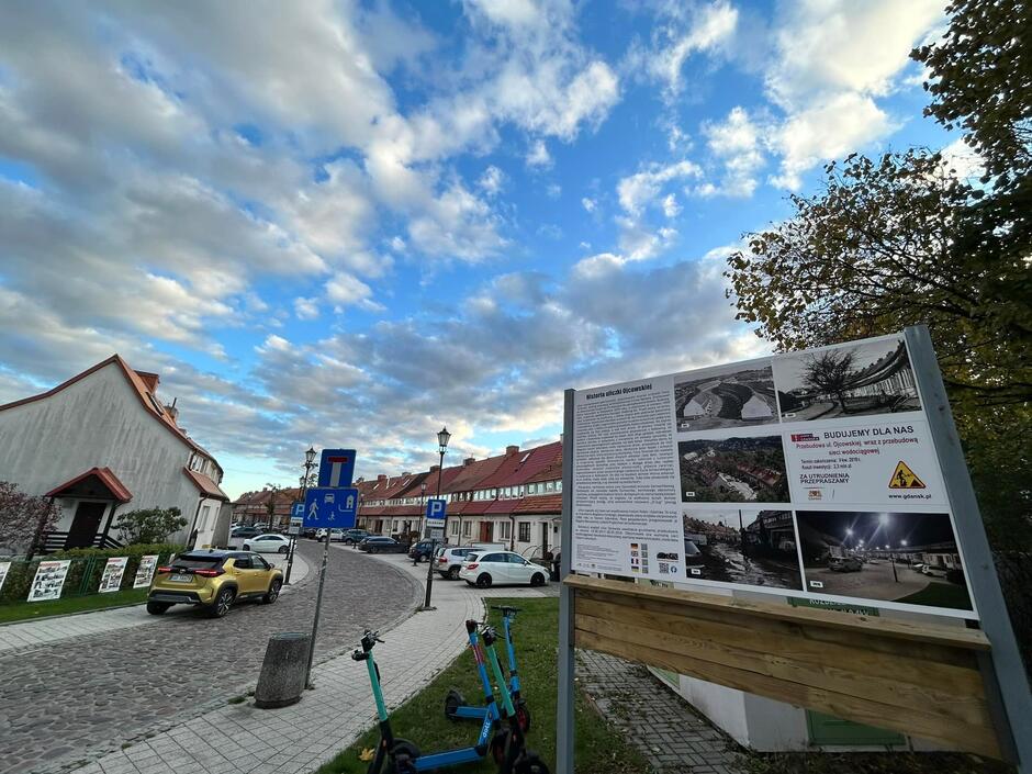 Tablica informacyjna o historii ulicy wystawiona przy chodniku.