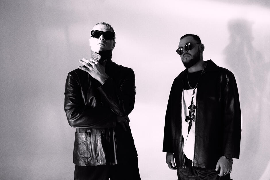 Na zdjęciu dwóch mężczyzn ubranych na czarno, w czarnych okularach przeciwsłonecznych.