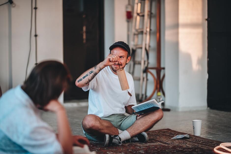 Na zdjęciu mężczyzna w siadzie skrzyżnym, siedzący na podłodze. 