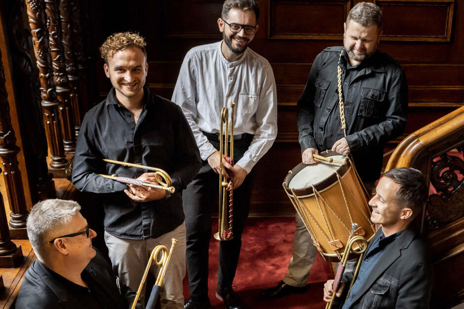 Pięciu mężczyzn z różnymi instrumentami muzycznymi.