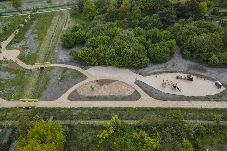 zdjęcie z drona, widać gęsto zarośnięty drzewami zielony teren, jest też kilka wyznaczonych alejek spacerowych