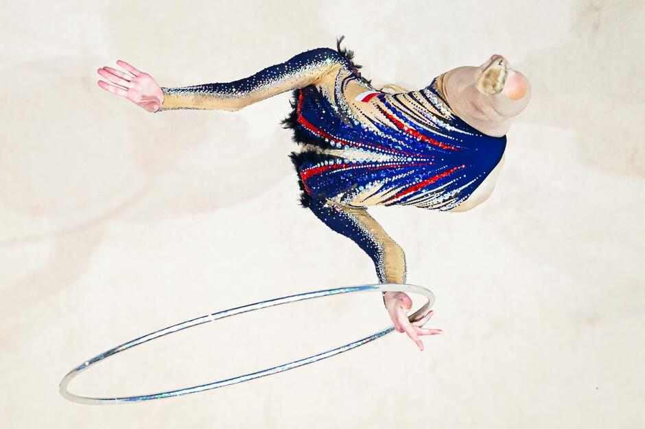 Zrobione z drona zdjęcie gimnastyczki w wyskoku - jej sylwetka jest tak pokazana, że nie widać głowy i nóg