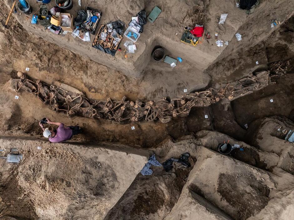 Widać m.in. długi wykop, w którym znajdują się ludzkie szkielety
