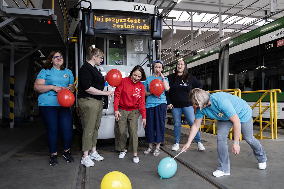 Przed tramwajem w hangarze w zajezdni stoi sześć kobiet z balonami.