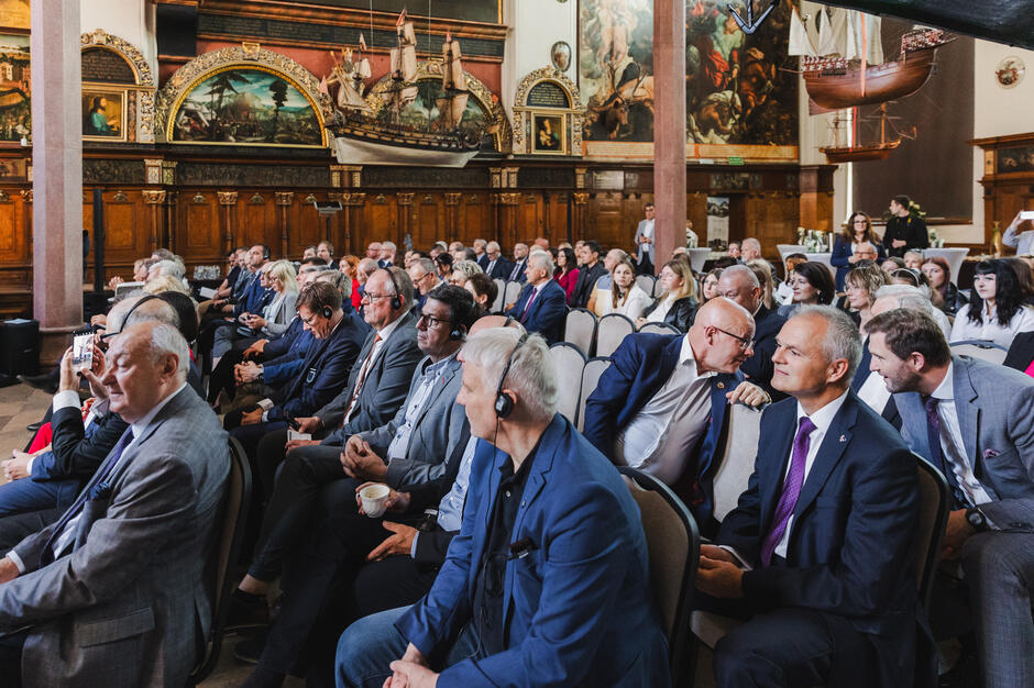 W reprezentacyjnej sali Dworu Artusa w Gdańsku siedzą na krzesłach słuchacze konferencji.