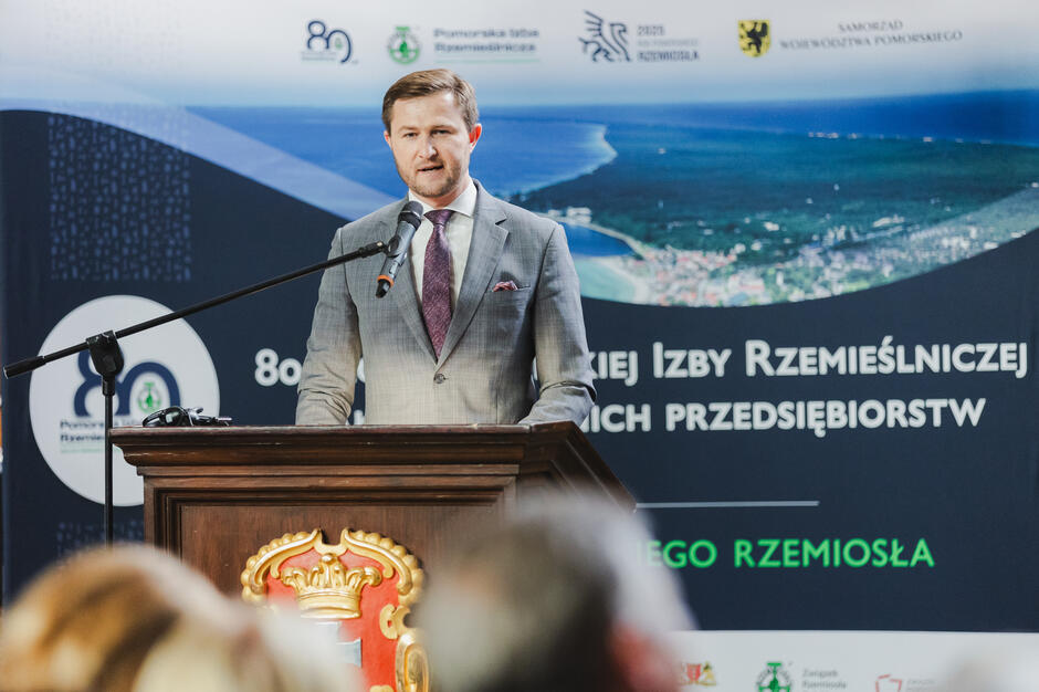 W reprezentacyjnej sali Dworu Artusa mężczyzna przemawia na mównicy.