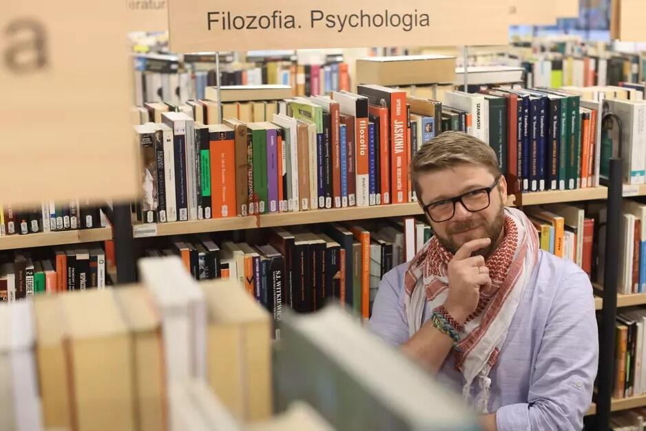 Na zdjęciu mężczyzna w okularach, w bibliotece pełnej książek. W tle napis filozofia i psychologia.