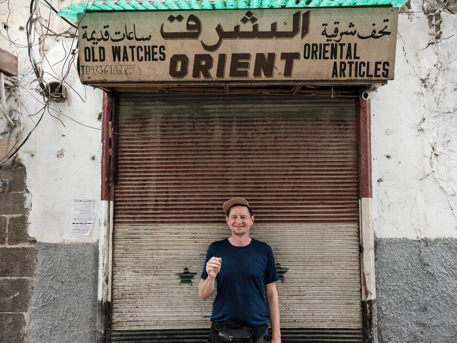 Na zdjęciu mężczyzna na tle szyldu z napisem orient.