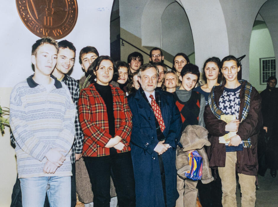 To zdjęcie przedstawia grupę uczniów i nauczyciela (lub zaproszonego gościa) w przestrzeni instytucji edukacyjnej – prawdopodobnie III Liceum Ogólnokształcącego w Gdańsku. Styl ubioru i jakość fotografii wskazują, że zostało wykonane w połowie lat 90..