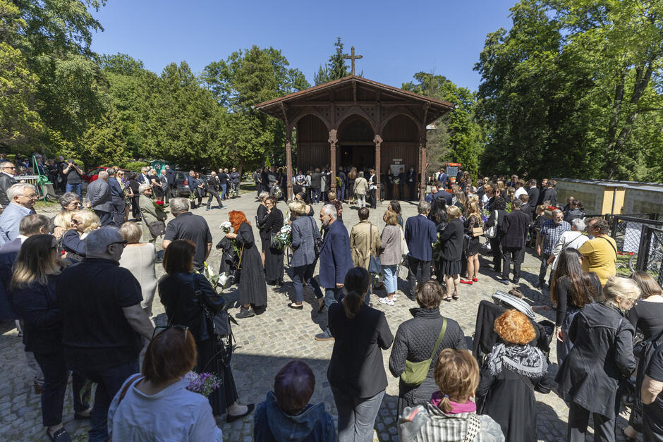 Stara drewniana kaplica cmentarna, wokół niej wiele osób