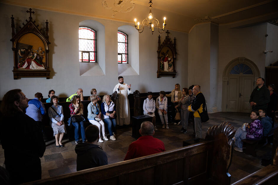 Dominikanin opowiada grupie ludzi w kościele o historii kościoła.