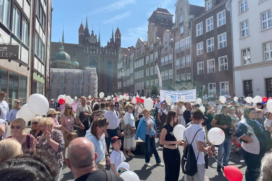 Tłum ludzi z transparentami na ulicy, w tle widać bazylikę mariacka w Gdańsku