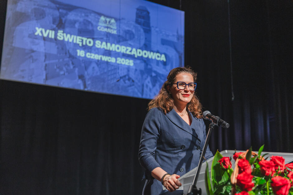 Kobieta przemawia na scenie z mównicy.