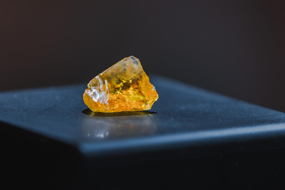 Średniej wielkości bursztyn leży na czarnym stole.