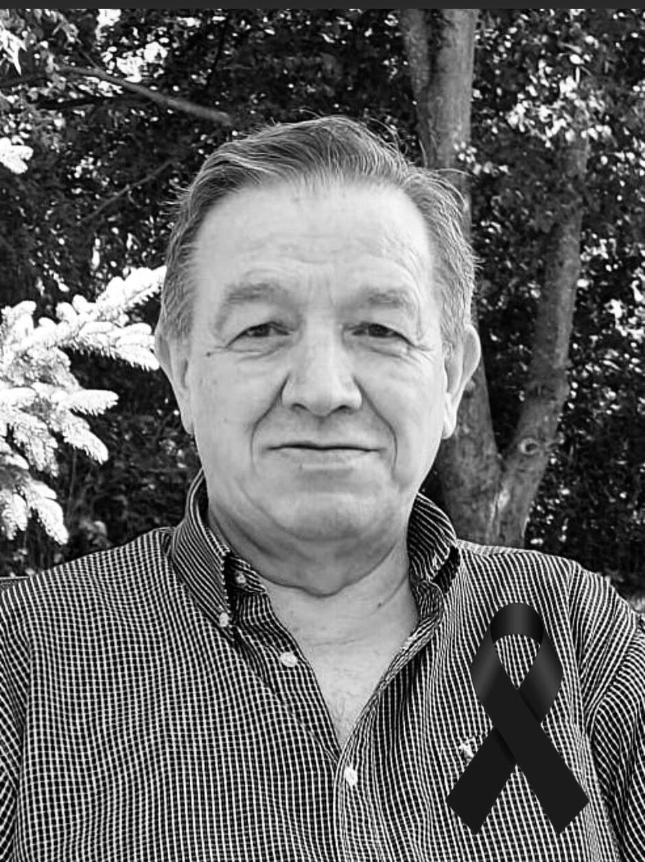 To to samo ujęcie mężczyzny w koszuli w kratkę, ale dodatkowo na jego piersi umieszczono czarną wstążkę żałobną. Zdjęcie także jest czarno-białe i ma charakter upamiętniający