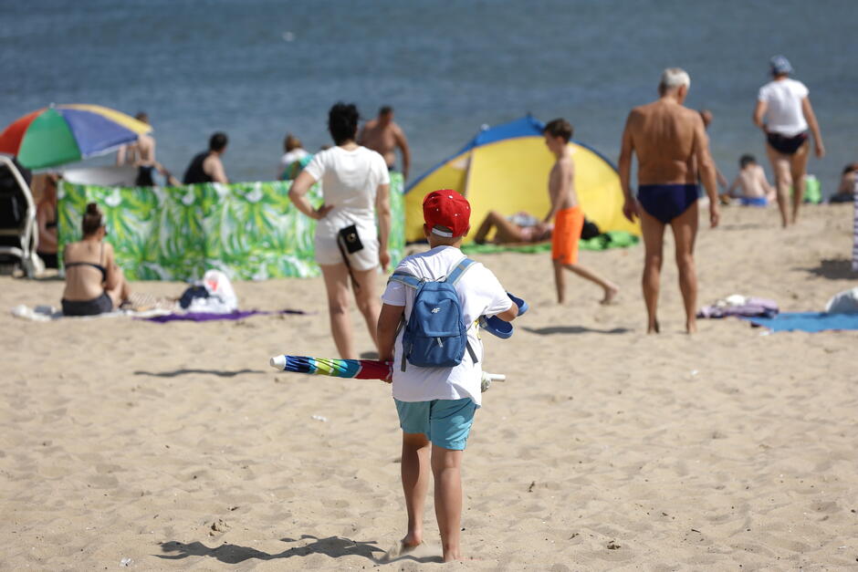 Grupa osób na plaży, w plażowych strojach