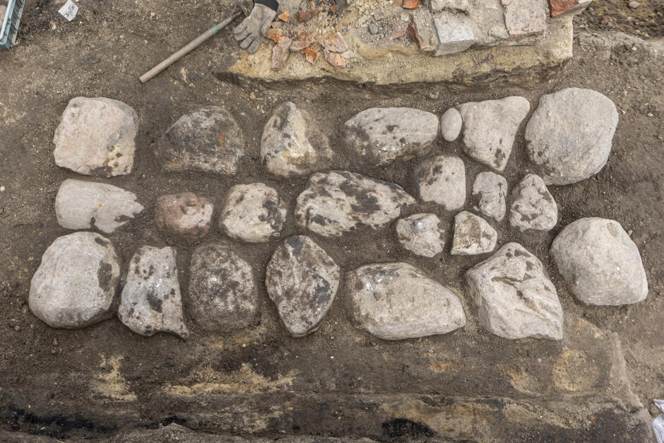 Leżące w ziemi duże kamienie - otoczaki, które razem tworzą kształt prostokąta 