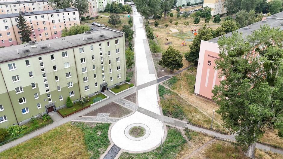 zdjęcie z drona, widać osiedle bloków mieszkaniowych, między nimi nowo budowany ciąg pieszo jezdny