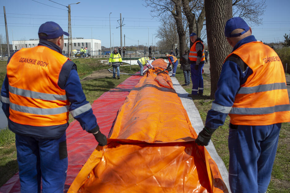 Ludzie z dmuchaną zaporą przeciwpowodziową
