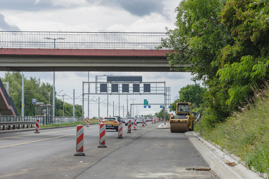 na zdjęciu jezdnia na której ustawiono znaki drogowe, w tle widać żółtą koparkę