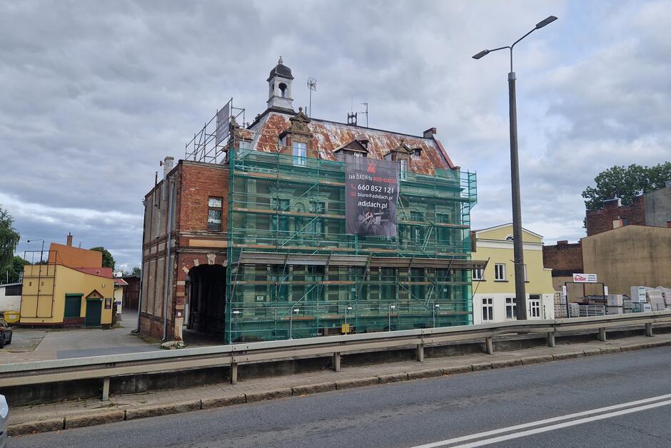 Kamienica zasłonięta rusztowaniem z zieloną siatką