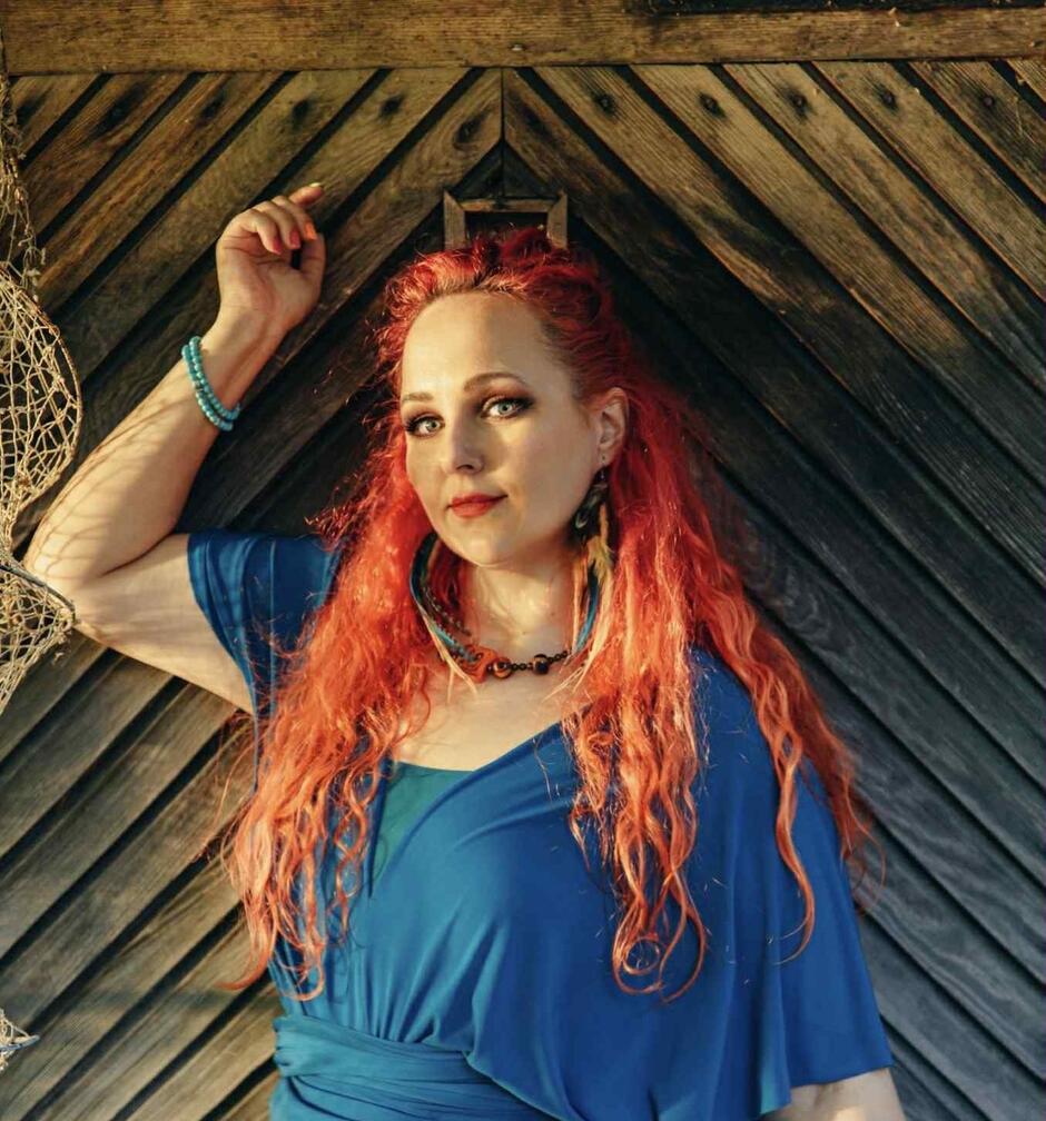 Na zdjęciu kobieta z długimi włosami, na sobie ma sukienkę.