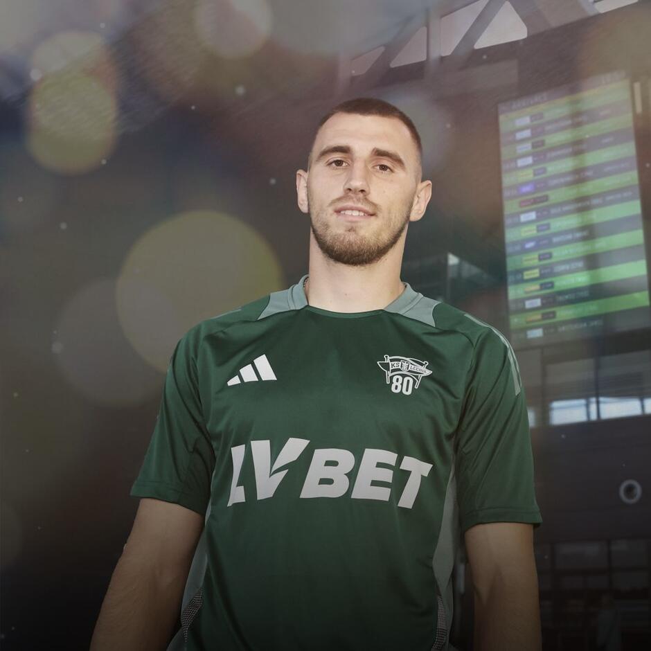 Młody mężczyzna w zielonej koszulce pozuje do zdjęcia